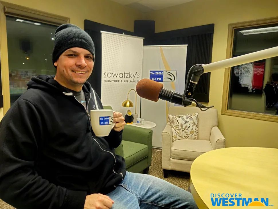 A young man sitting and smiling at the camera